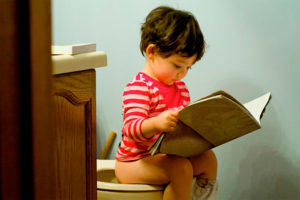 Ребенок сидит на горшке и читает книжку